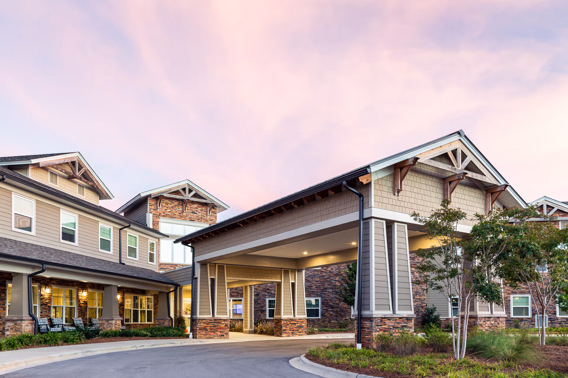 Sunset sky above HarborChase of Riverwalk exterior with covered entrance and landscaped grounds.