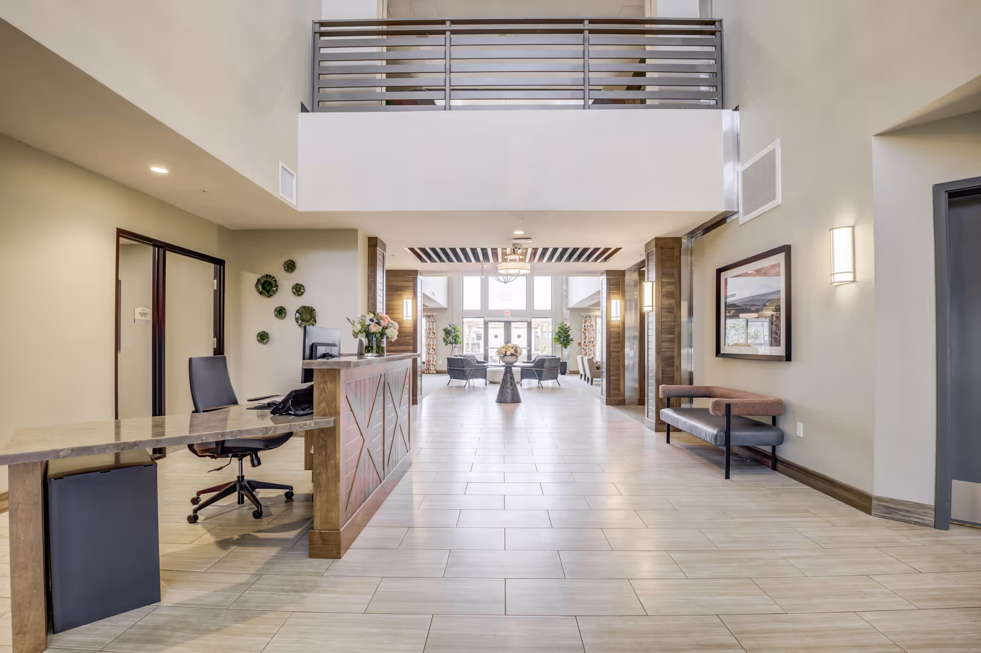 Bright, modern lobby with a reception desk, seating areas, and a mezzanine balcony.
