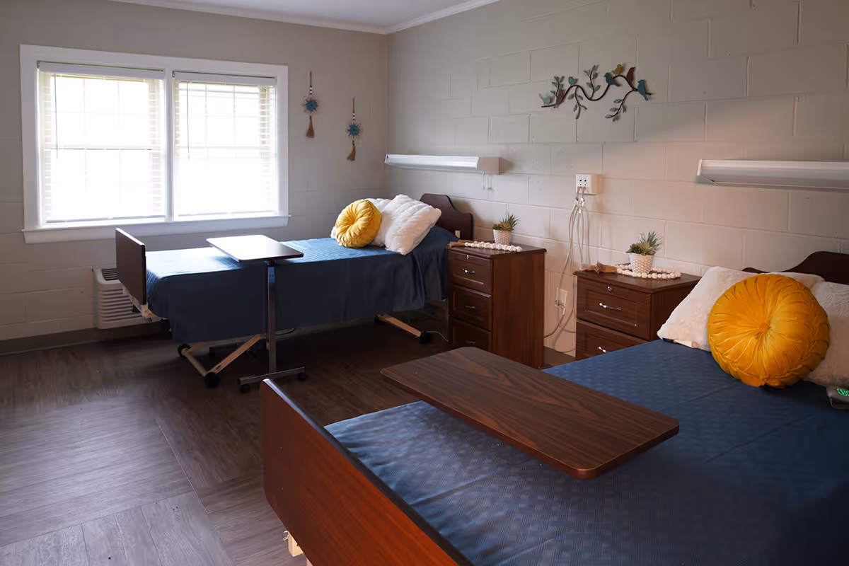 Two blue beds with yellow round pillows and nightstands in a bright bedroom.