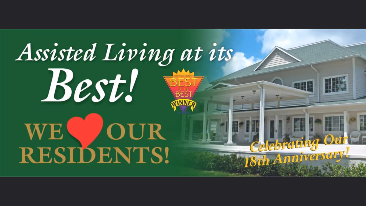 Exterior view of Cedar Creek ALF with a large green promotional banner over the entrance reading 'Assisted Living at its Best! We ♥ Our Residents! Celebrating Our 18th Anniversary!'.