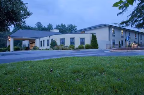 Exterior view of The Laurels of Summit Ridge facility with a driveway and lawn.