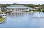 Lakeside senior living building with a covered porch, gazebo, and a fountain in the pond.