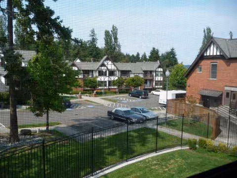 Exterior view of Franke Tobey Jones campus with buildings, trees, cars, and a fence.