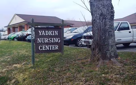 Exterior view of Yadkin Nursing Center with a sign and parked cars