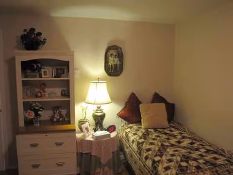 Cozy bedroom with quilted bed, lamp, and a dresser with decor