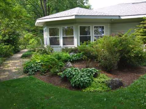 Front view of a single-story senior living home with large windows and shrubs.