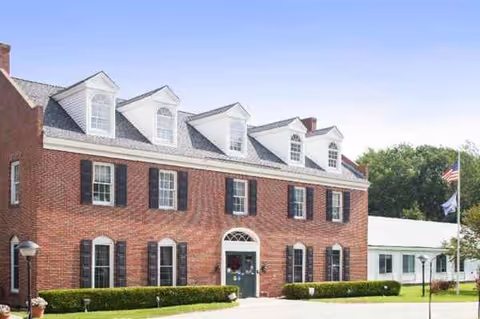 Front view of Birch Healthcare Center: red brick facade, dormer windows, green door.
