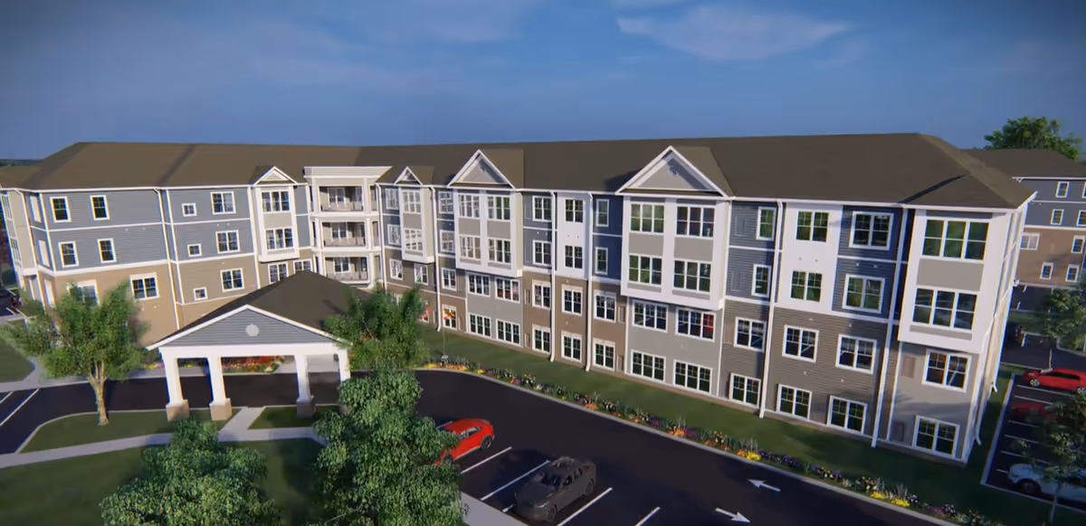A large multi-story senior living facility facade with front entry canopy and parking.
