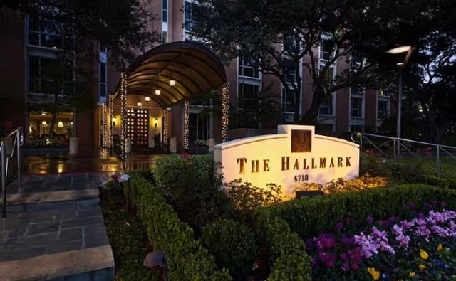 Entrance to The Hallmark senior living facility with illuminated sign and landscaped front.