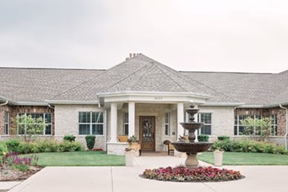 Front exterior view of Volante Senior Living of Arlington Heights with a fountain and landscaping.