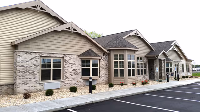 Front exterior of Lilac Springs Assisted Living Center with brick and beige siding, parking lot.