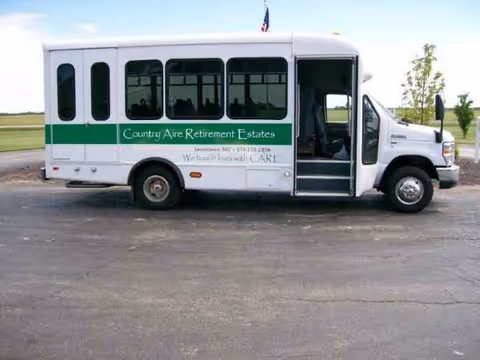 White shuttle bus for Country Aire Retirement Estates parked outside with open door