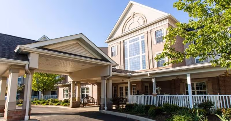 Senior living facility entrance with covered driveway and brick building facade.