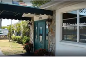 Entrance of Manatee River Assisted Living showing green double doors with an oval window, stone-faced entry, and a green awning.