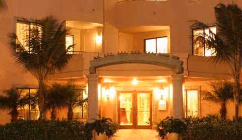 Night view of Atria La Jolla entrance with warm lights and palm trees.