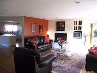 Cozy senior living lounge with leather seating, coffee table, rug, and a fireplace.