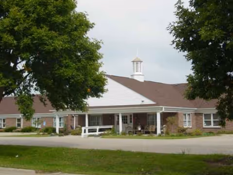 A single-story senior living facility with a covered entrance and white cupola.