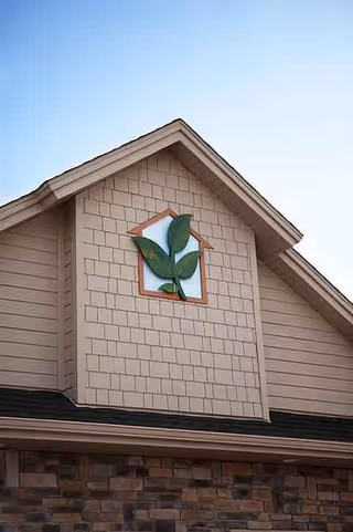 Exterior of Bavarian Comfort Care senior living facility with green leaf logo on the gable.