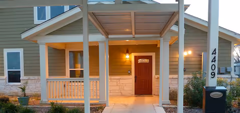 Front entrance of Mercy House Victoria with a covered porch and wooden door.