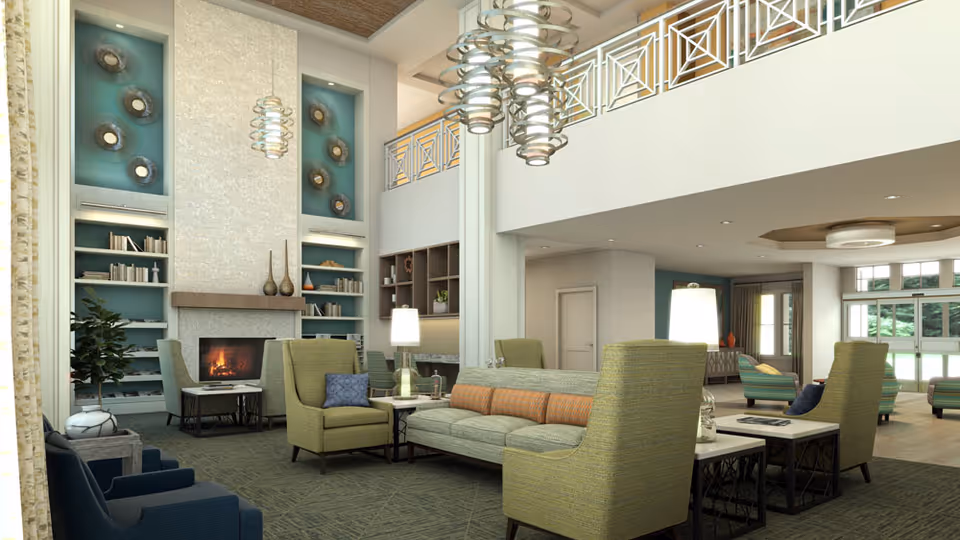Spacious two-story communal living room with sofas, armchairs, a fireplace, built-in bookshelves, and modern pendant lighting.