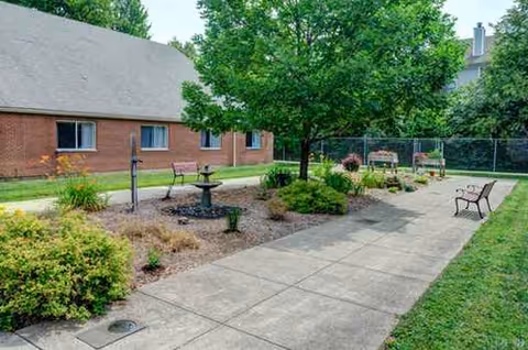 A paved path runs through a landscaped outdoor courtyard with benches and a central fountain.