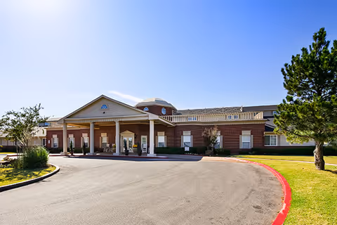 Brick exterior of a senior living facility with a covered entrance and curved driveway.
