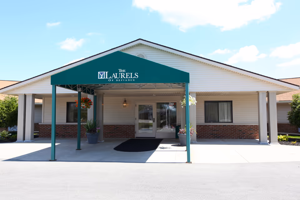 Front entrance of The Laurels of Defiance with a green covered awning over the doorway.