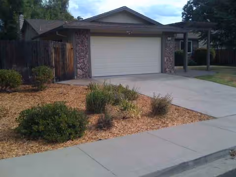 Front view of a single-story home with a two-car garage and landscaping.