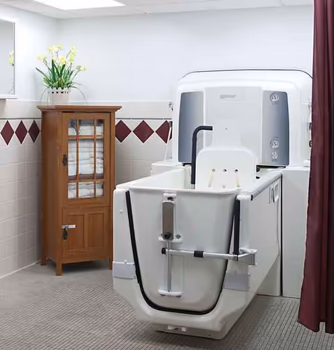 A large white medical machine sits beside a wooden cabinet in a clean clinic room.