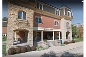 Exterior front view of a multi-story retirement center building with stone and brick facade, featuring a covered entrance with the sign 'Bethany Home' above it, surrounded by landscaping and a sidewalk.