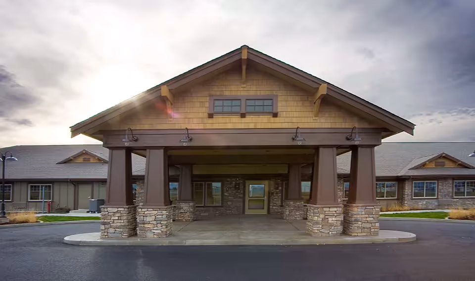Front view of Creekside Inn Memory Care Community entrance with stone pillars.