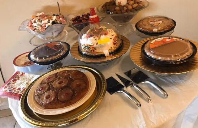 A dessert spread on a multi-tiered table with cakes, cupcakes, and chocolates in dining area.