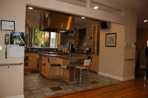 Open kitchen with island, bar stools, and appliances in a senior living facility.