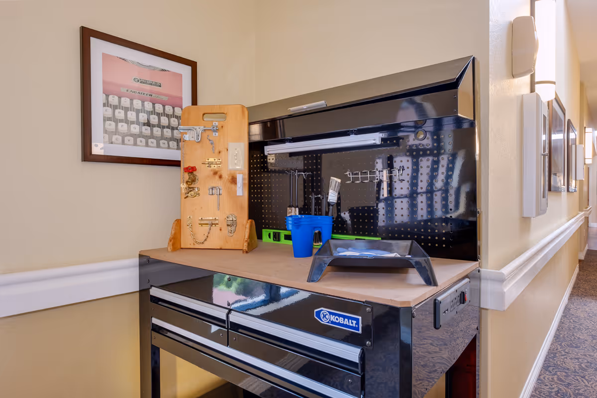 A Kobalt tool chest workstation topped with a wooden activity board and tools set up along a carpeted hallway.
