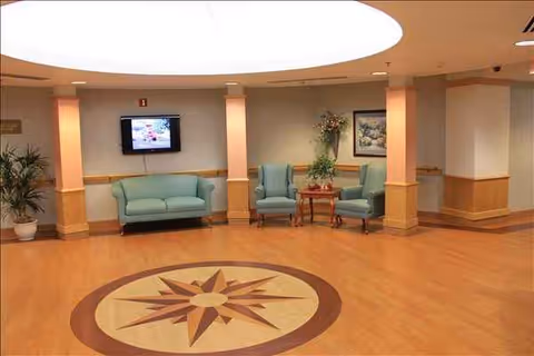 Independence Court lobby with teal seating, plants, a wall TV, and compass floor design.