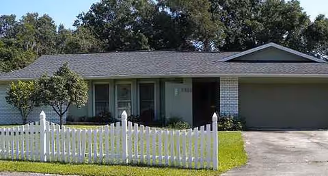 Front exterior of Honor House Assisted Living Facility with a white picket fence.