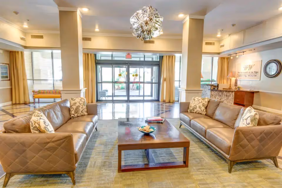 Bright lobby seating area with two sofas facing a coffee table and glass double doors at the back.