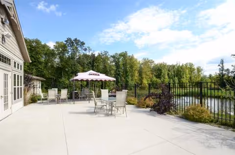 Outdoor patio at The Waterford at Plymouth I with seating, umbrella, and pond.