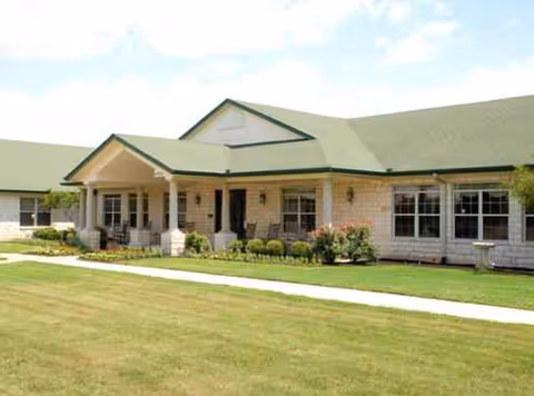Single-story senior living facility with green roof, front entrance, and manicured lawn