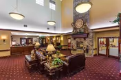 Spacious lobby with leather sofas arranged around a stone fireplace, high ceilings, pendant lights and a reception desk in the background.