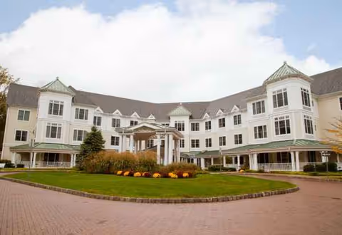 Sunrise of Randolph facility exterior with white curved wings and manicured lawn