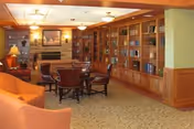 Comfortable lounge with sofas, armchairs, a central table, fireplace, and built-in bookshelves along one wall.