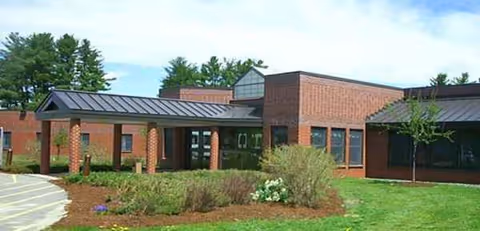 Brick senior living facility with a covered entrance and landscaped front yard.