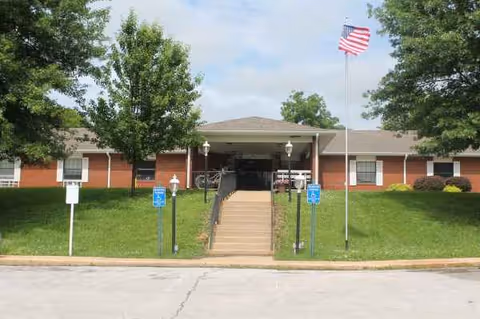 Front exterior of Buffalo Prairie Care Center with entrance stairs, flag, and lawn.