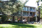 Three-story senior living building with balconies and a green lawn.