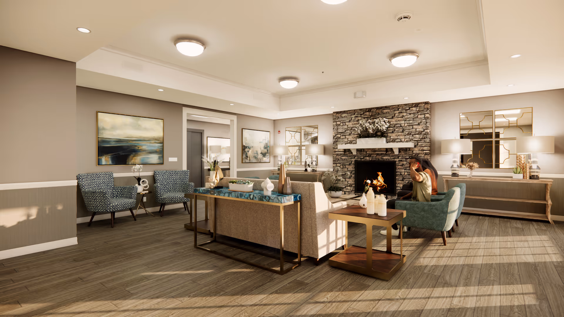 A cozy assisted living facility common area with a stone fireplace, a fire burning inside, and comfortable seating including armchairs and sofas. The room has wooden flooring, neutral-colored walls, modern ceiling lights, decorative mirrors, and artwork on the walls. A person is sitting on one of the armchairs near the fireplace.