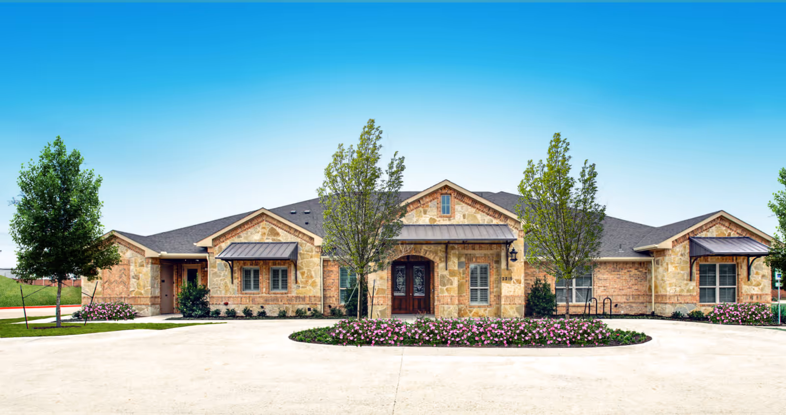 Front view of a single-story stone Avalon Memory Care building with landscaped entrance.