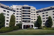 A multi-story senior living building with a central glass atrium and manicured lawn.