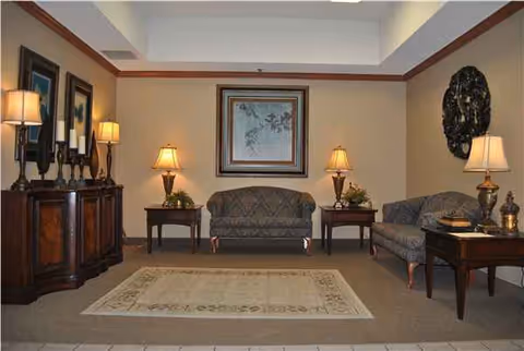 A spacious resident lounge with sofas, end tables, lamps, and framed artwork.