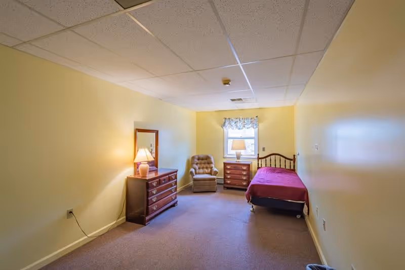 Pleasant Ridge bedroom: a cozy room with a bed, two dressers, an armchair, and lamps.